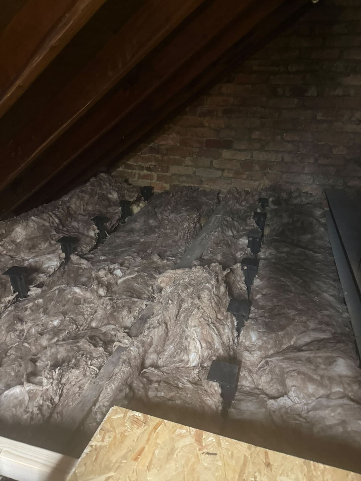 Loft insulation laid alongside the edge of the boarded floor