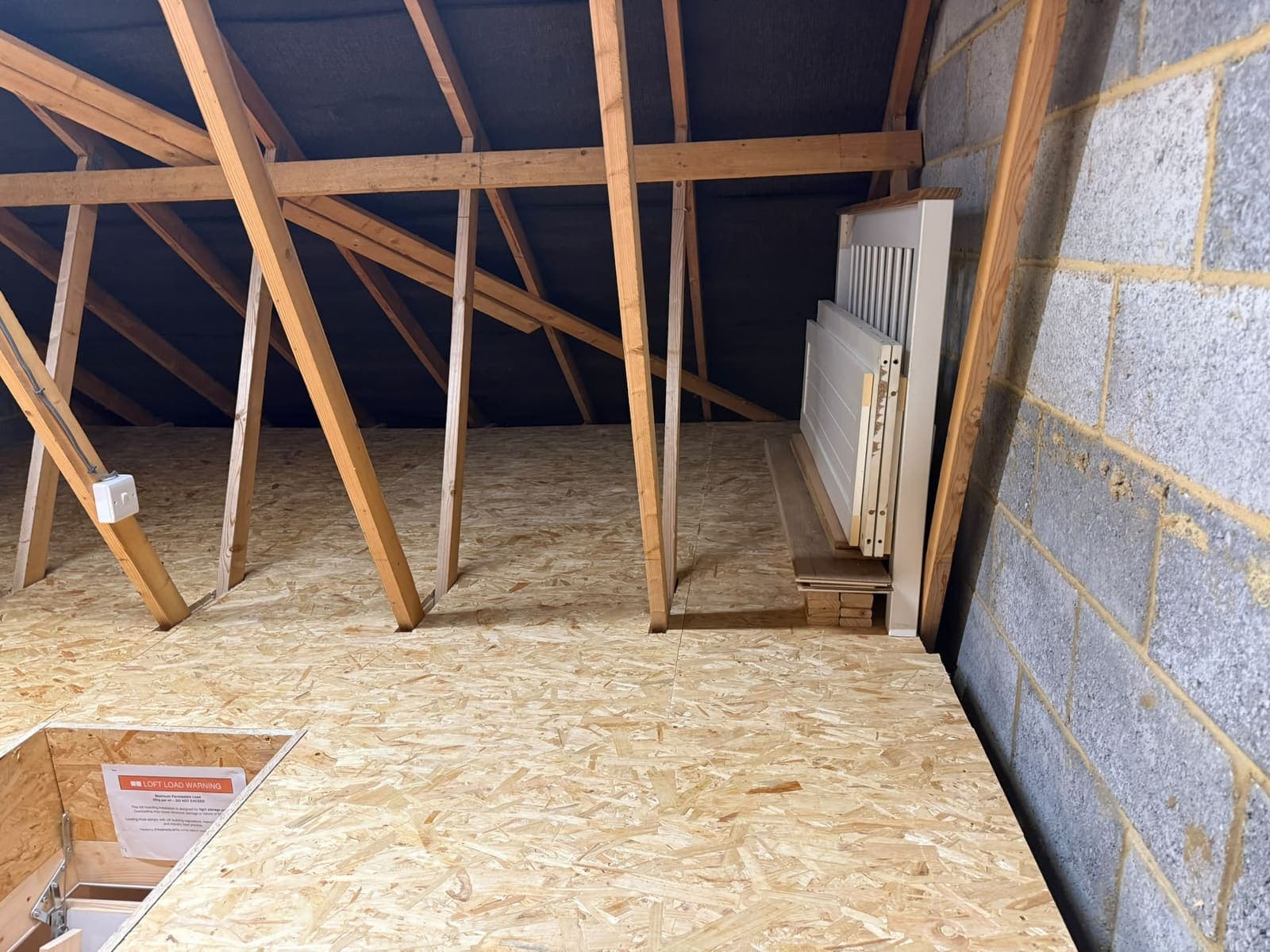 Loft boards run up to the blockwork gable wall beside the new hatch