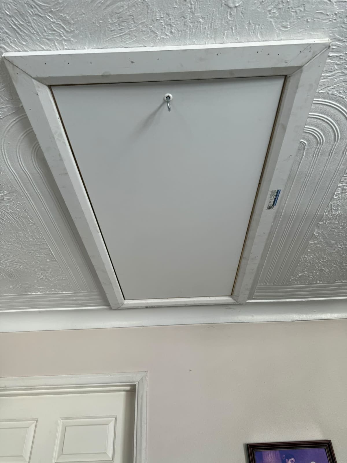 Loft hatch closed and trimmed against a textured ceiling