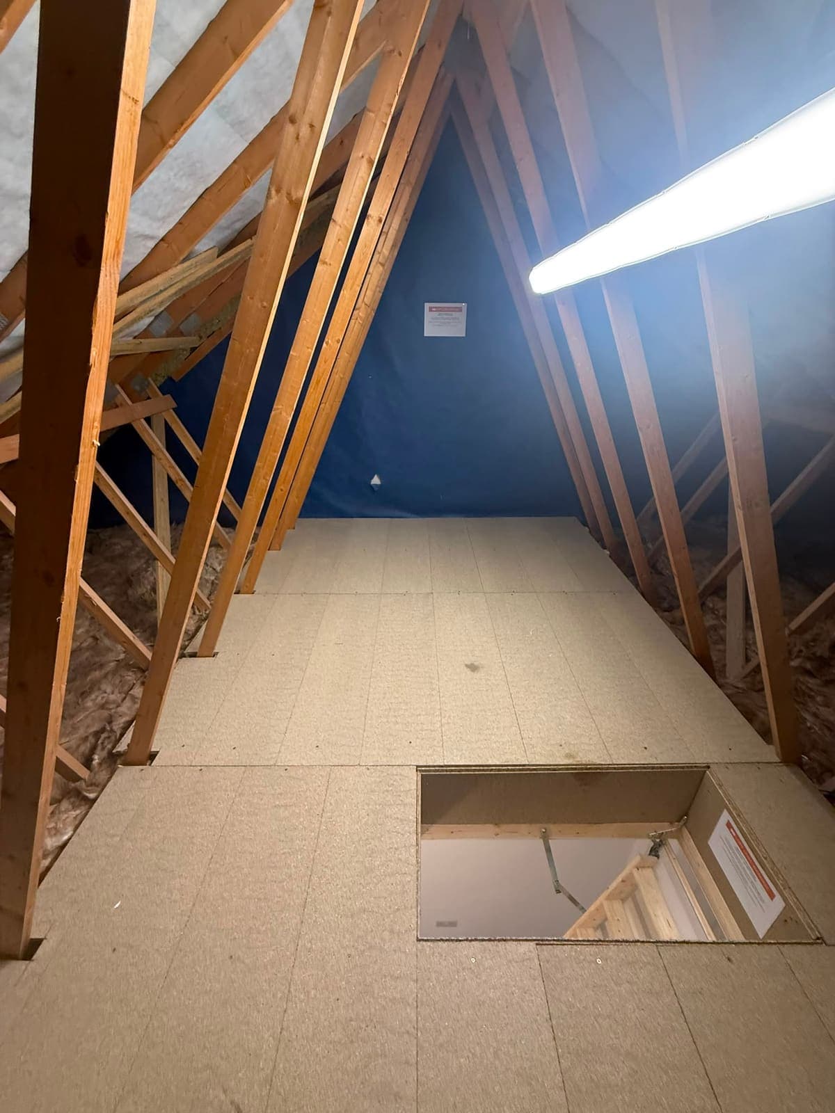 Boarded loft floor and hatch lit by a strip light in a Kent new build