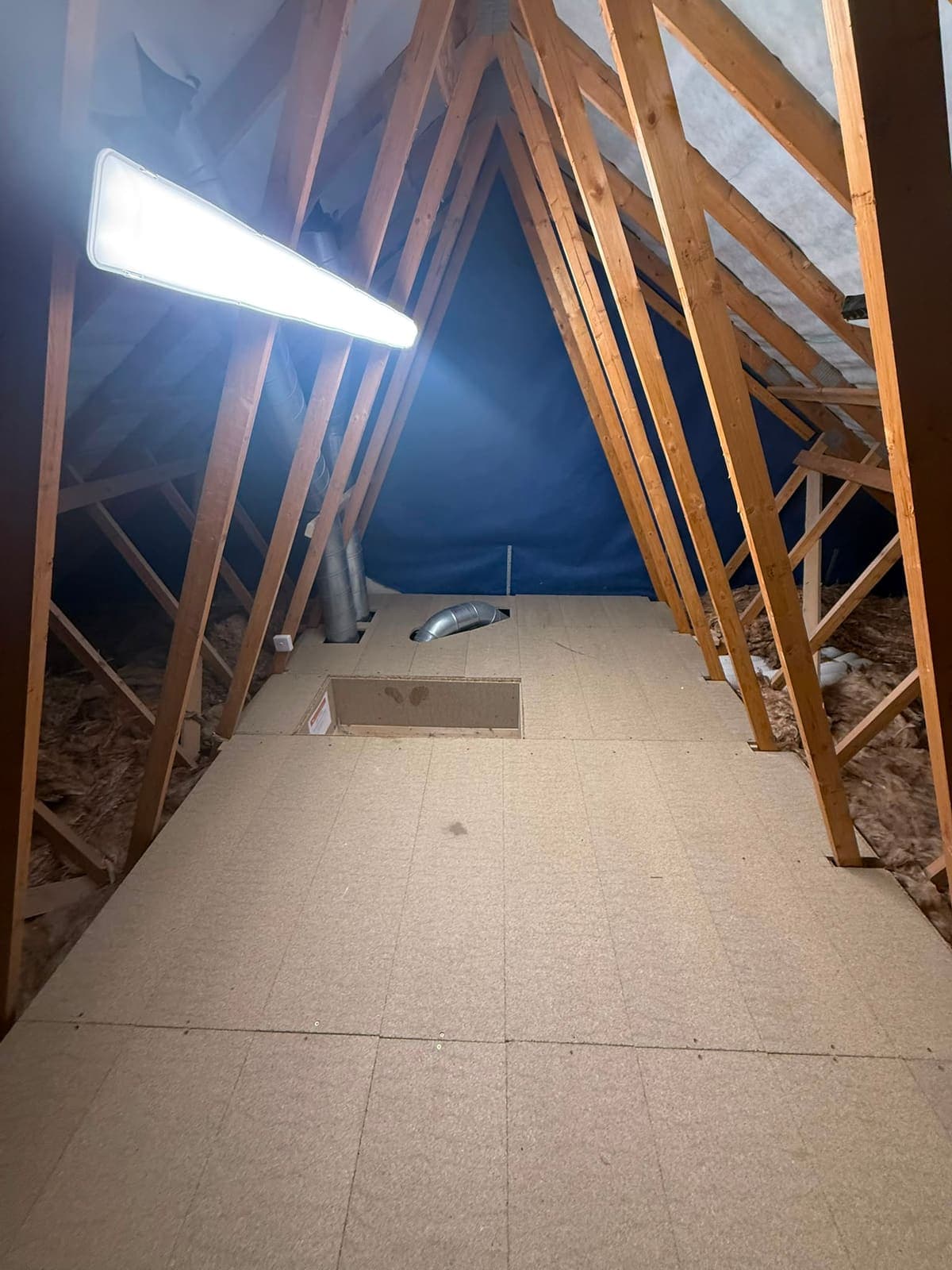 Boarded loft floor with strip lighting in a trussed roof