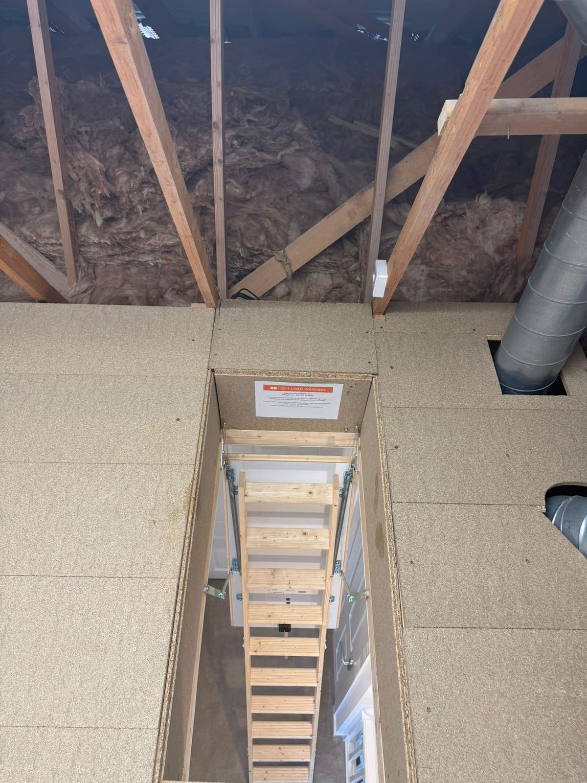 Looking down a wooden loft ladder through the boarded hatch